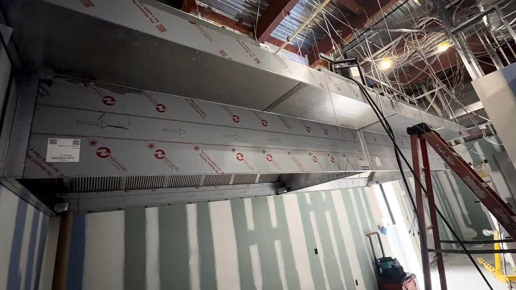 Technician cleaning a commercial kitchen exhaust system